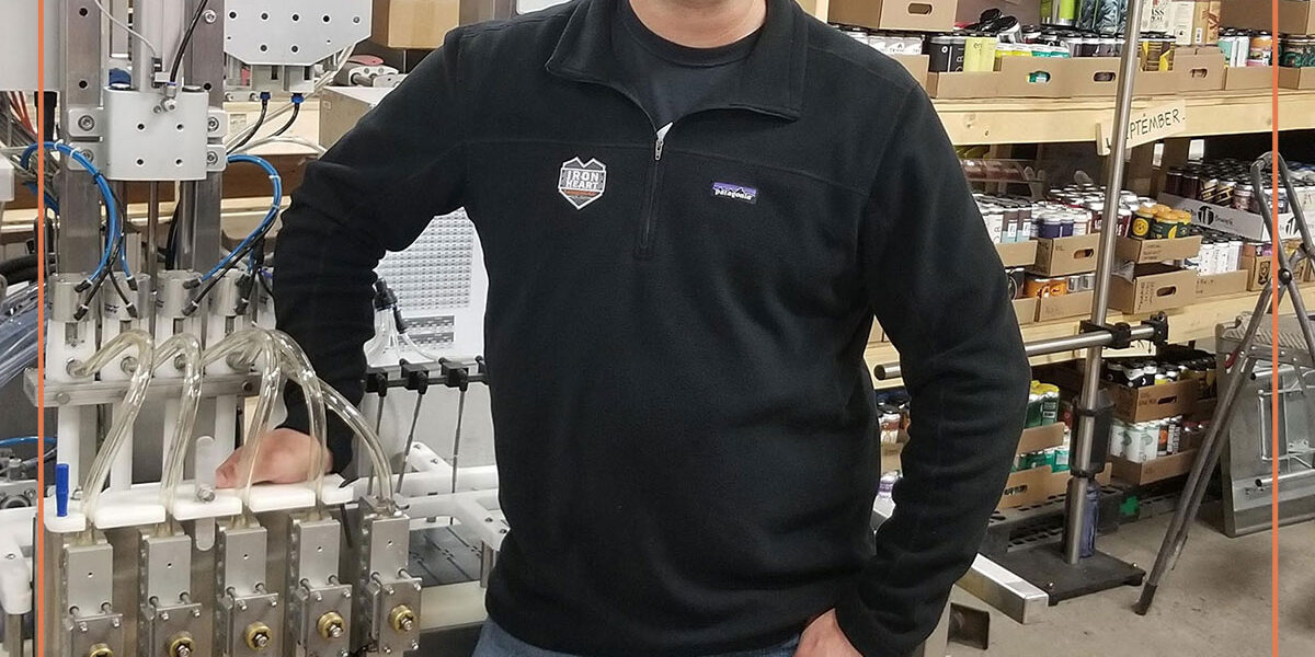 Mark, the VP of Special Projects and Services and creator of the technical support program, standing in front of a canning line